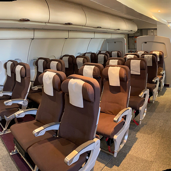 Seating area of Airplane Cabin mock-up, including life jackets, seatbelts, and overhead bins at the HAE Training Facilities.